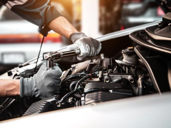 Automechaniker beim Anziehen einer Schraube im Motorenblock